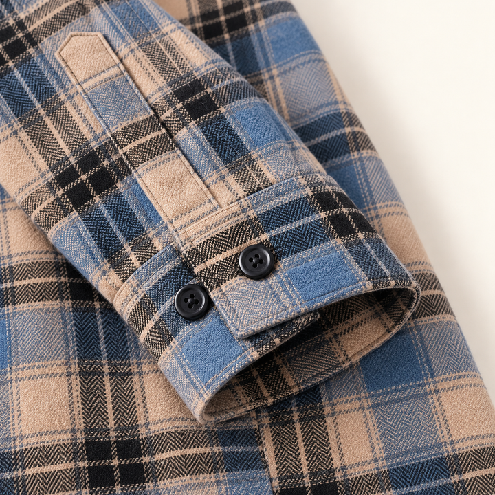 Close-up of a blue and beige plaid flannel cuff, black buttons and fine woven fabric.