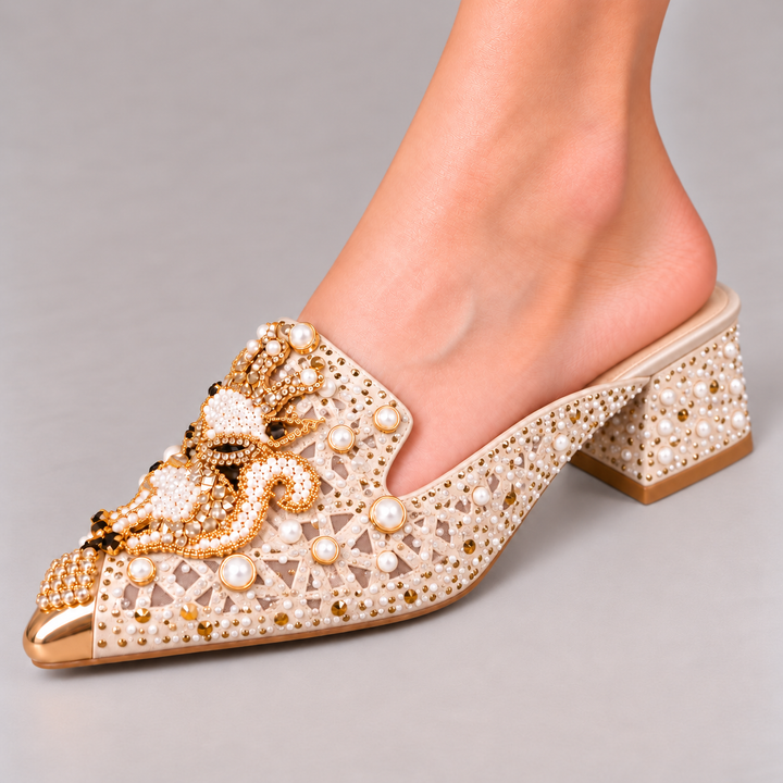 Khaki Odette mule worn on foot, facing left in a close-up studio view showing the cutout upper, pearl and gold-tone embellishments, pointed toe and block heel.